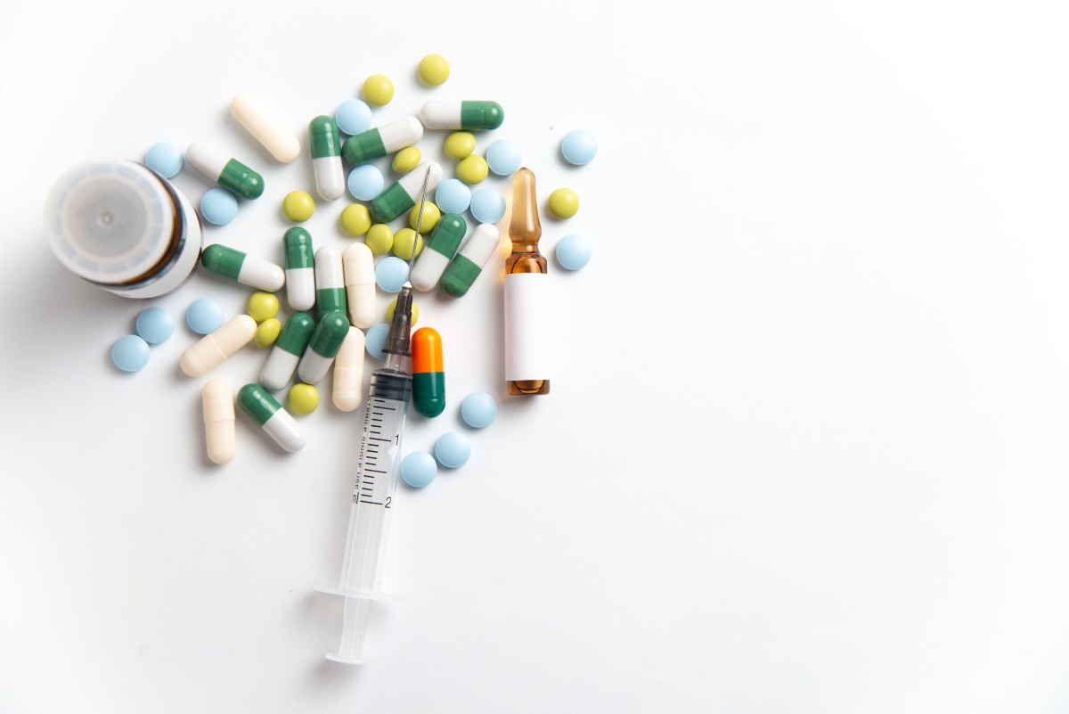 a smattering of pills and drug paraphernalia on a white background.