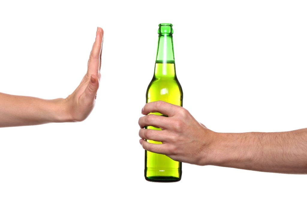 A hand blocking a green bottle on a white background.